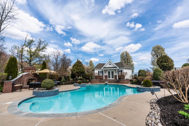 A pool in a backyard with a small pool house.