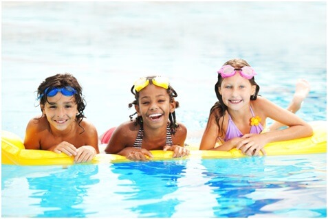 Three children swimming in a pool.