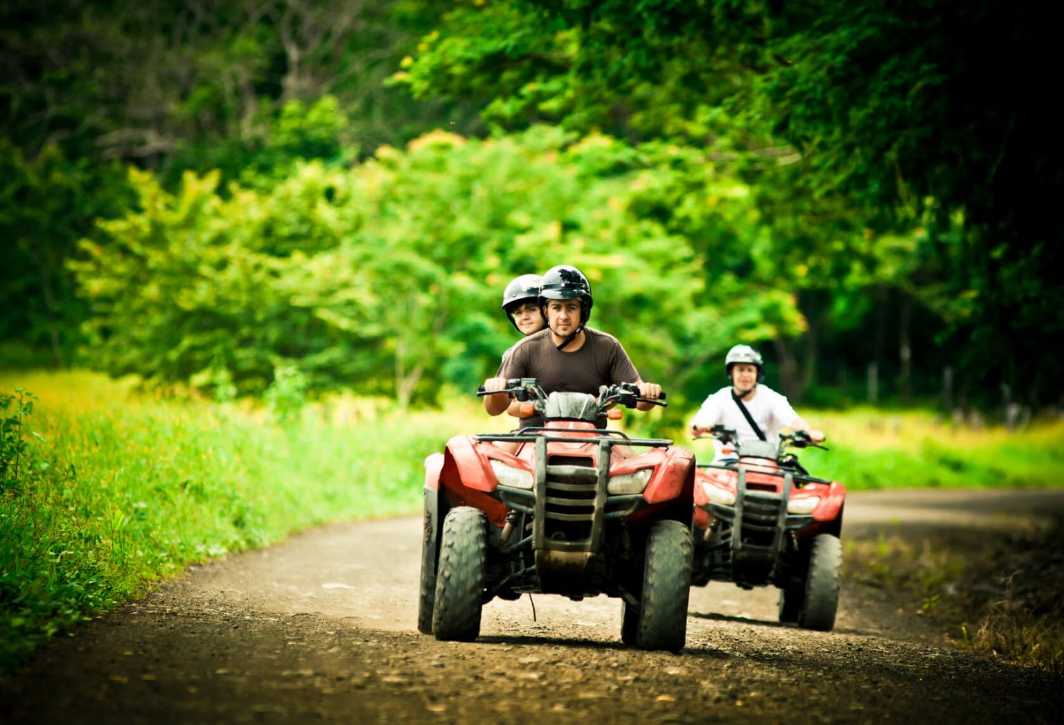 Two ATV riders with one passenger.