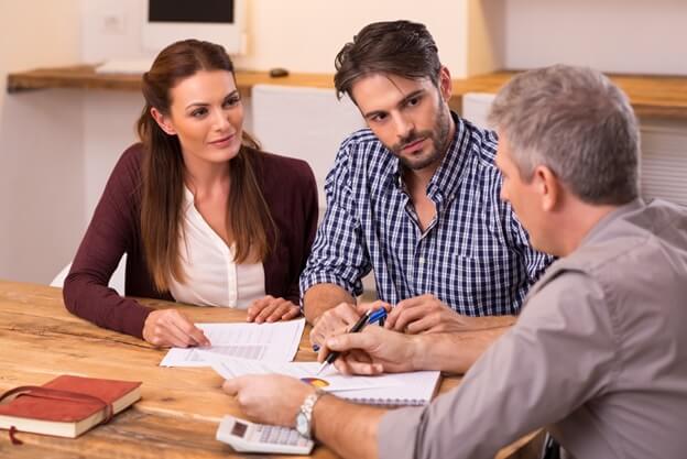 An insurance broker talking to a couple at a table.