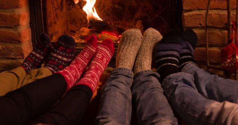 Four pairs of feet warming by a fire