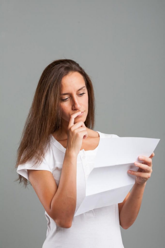 A woman looking at a piece of paper with a pensive look.