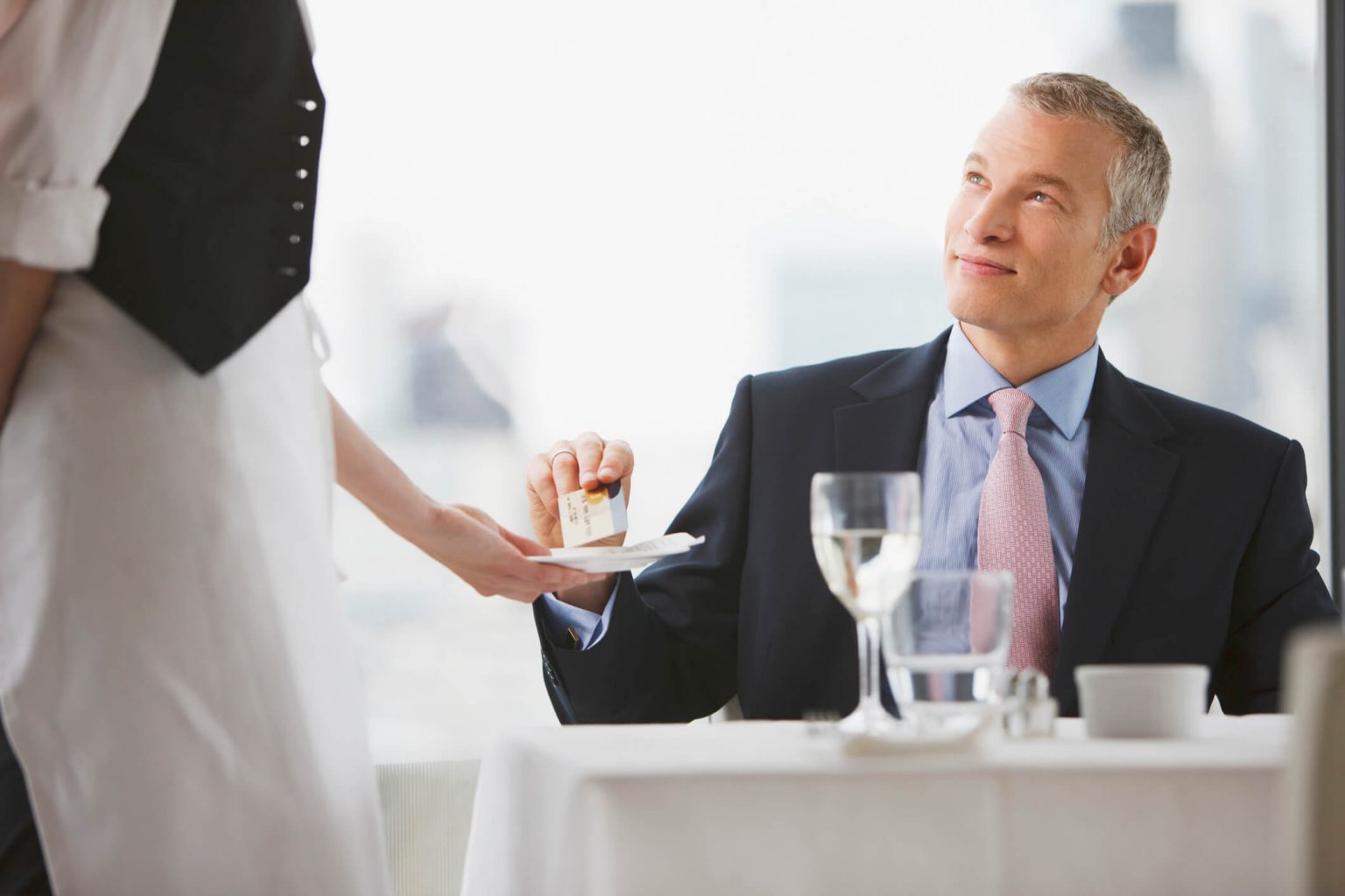 A business man handing a credit card to a waiter.