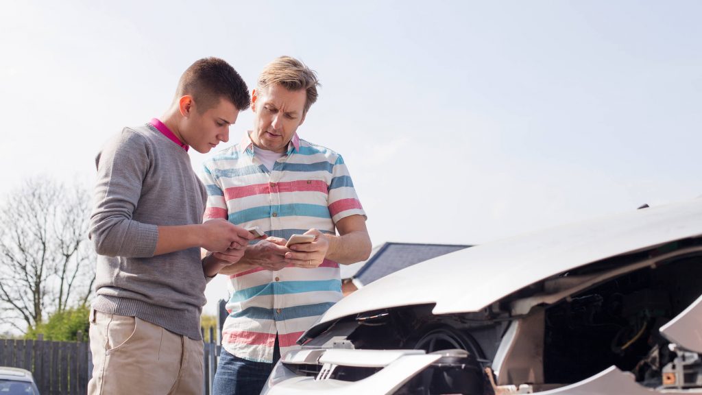 Two people exchanging information in front of a damaged car.