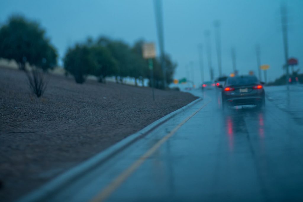 A rainy wet road with cars on it.