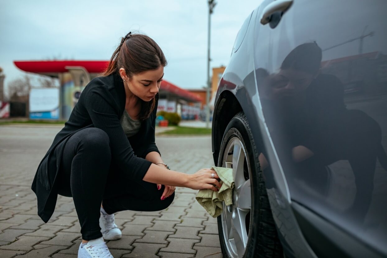 A woman looking at her car tire