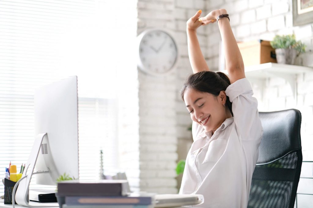 A woman stretching at her work desk