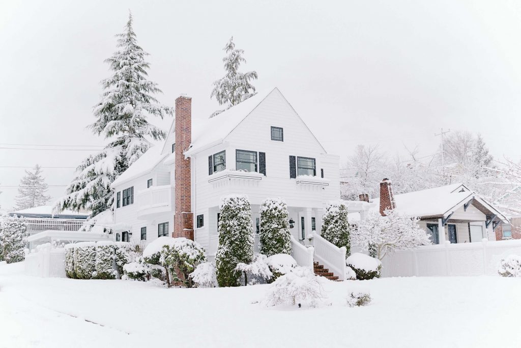 A white house in the winter surrounded by snow