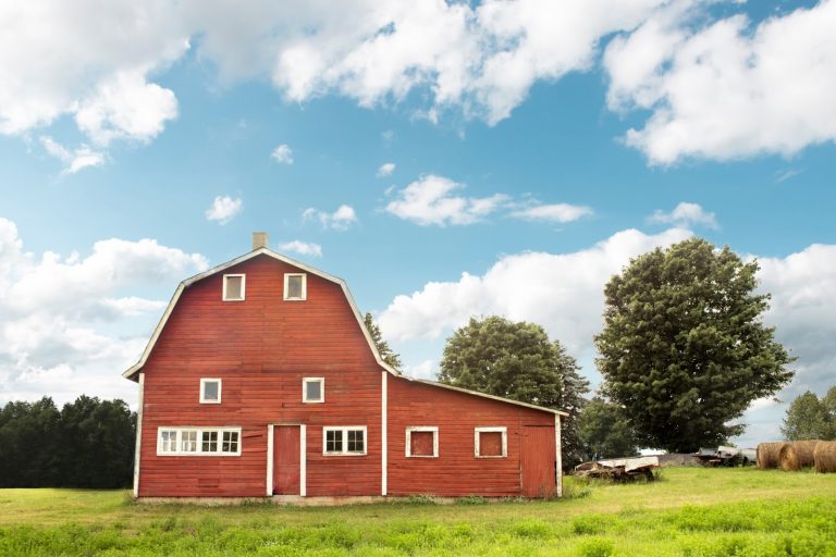 a red barn with blue skies and green grass