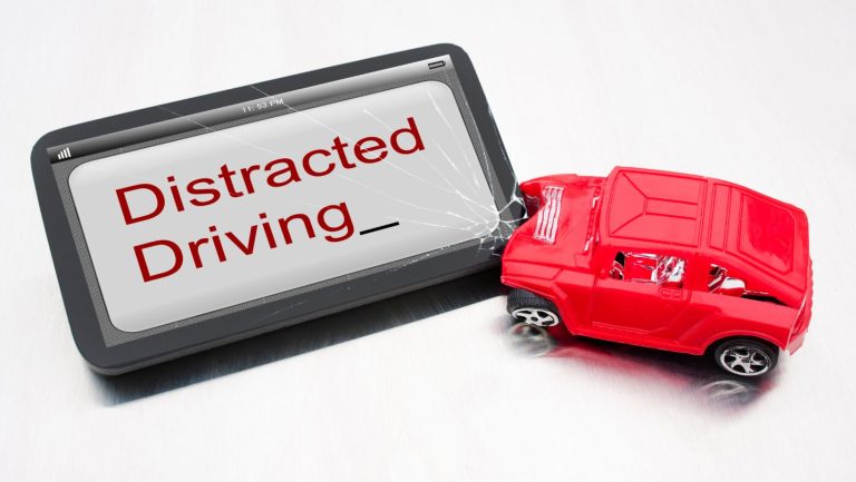 A toy car crashed into a tablet that says distracted driving.