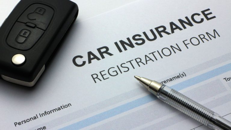 a car insurnace registration form with a pen and car key on top.