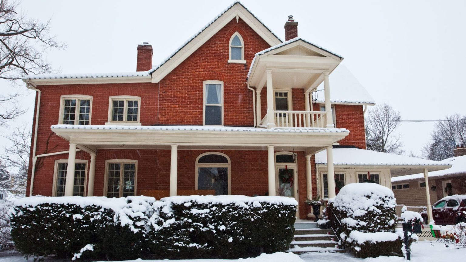 a red bricked home with snow all around it and a car in the driveway