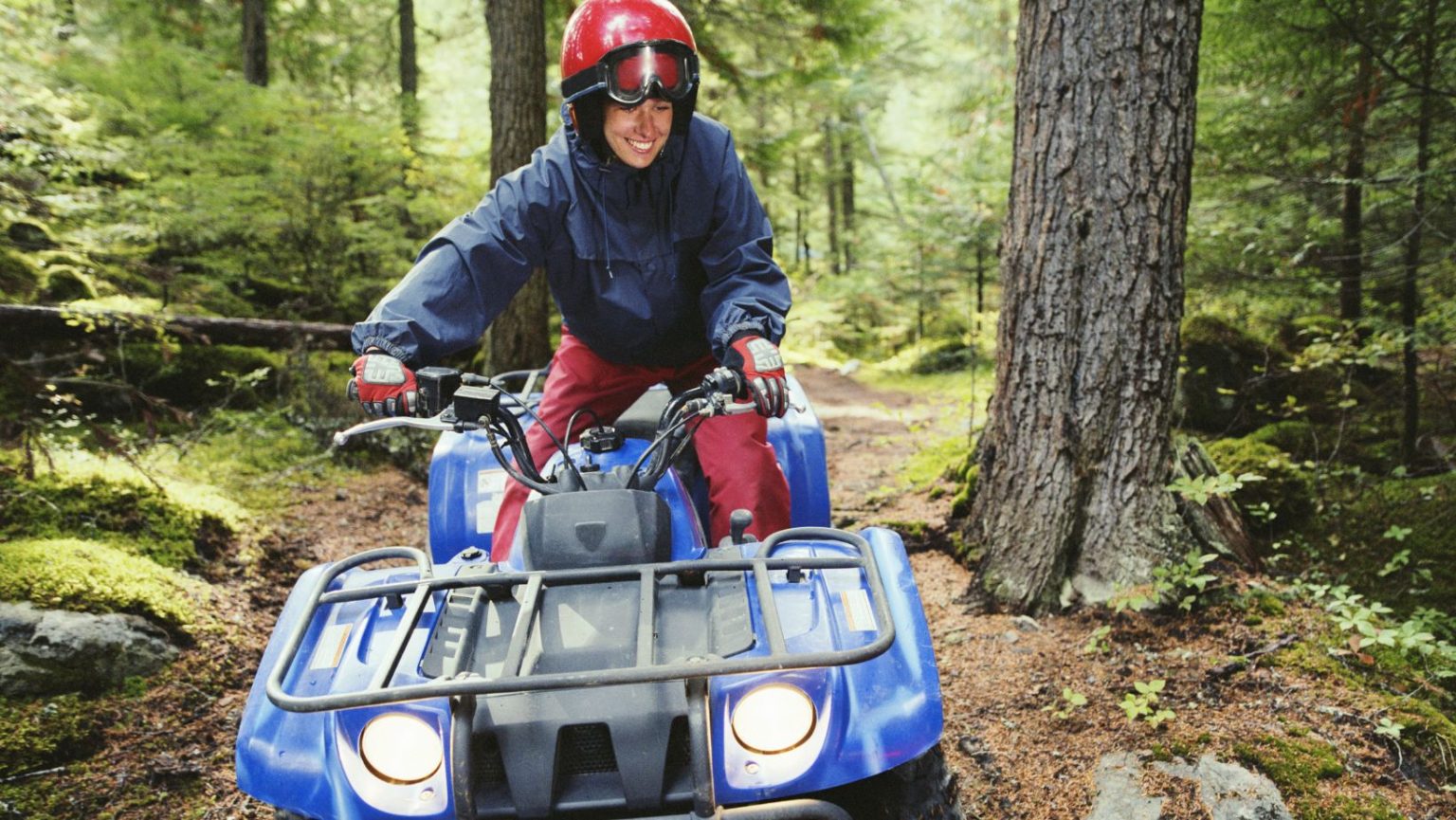 A person riding a atv through a forest.