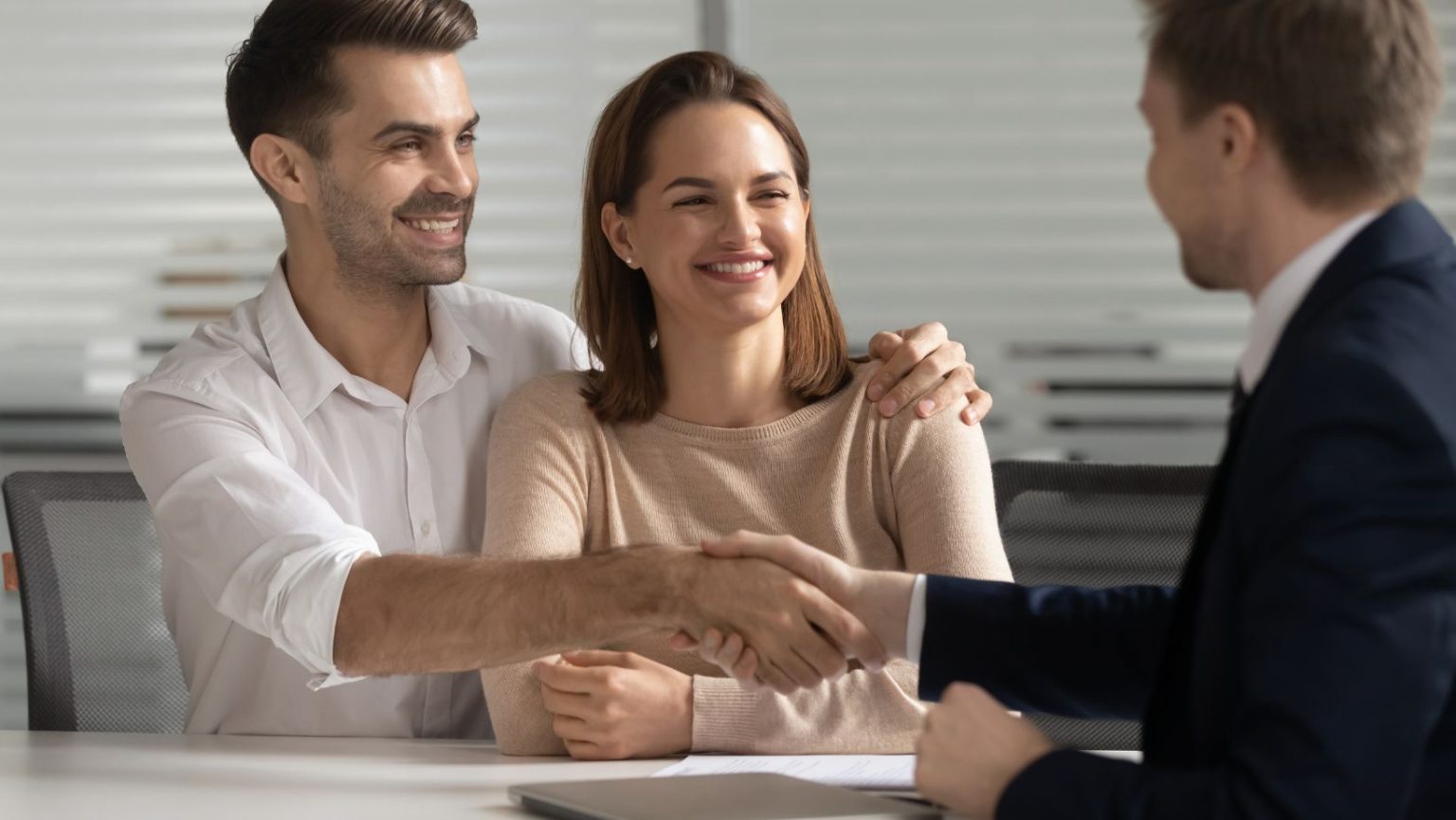 A couple with the man shaking another persons hand.