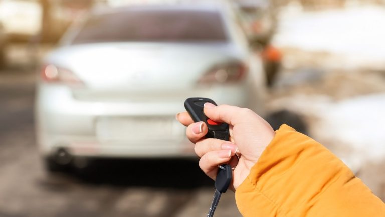 a person holding a car key fob clicking a button for their car