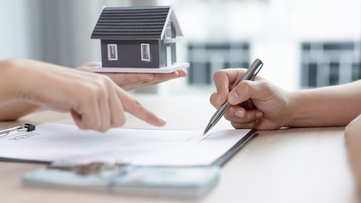 someone holding up a tiny home model while pointing to insurance papers.