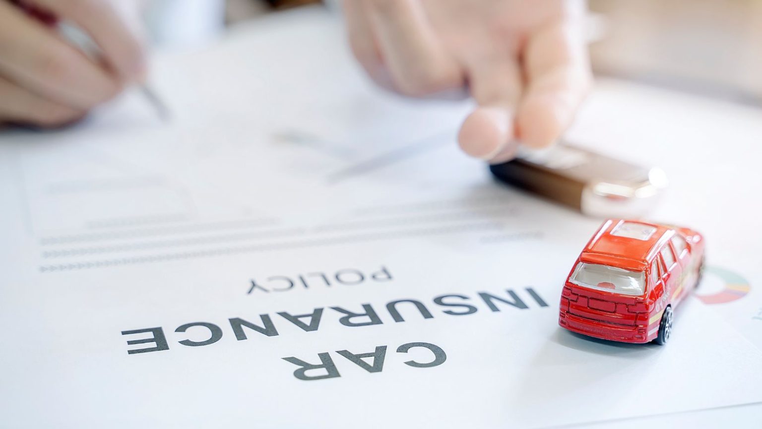 A close-up of a toy car on a car insurance document.