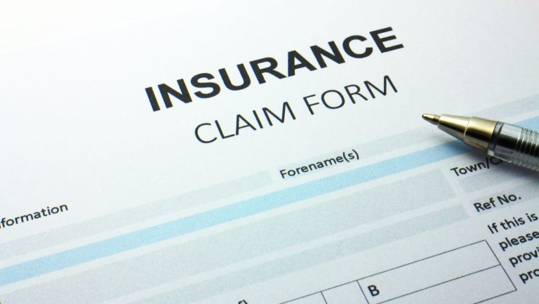 Insurance claim form being filled out with a pen.