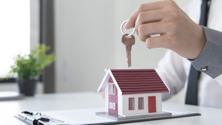 A man holding a key above a house model.