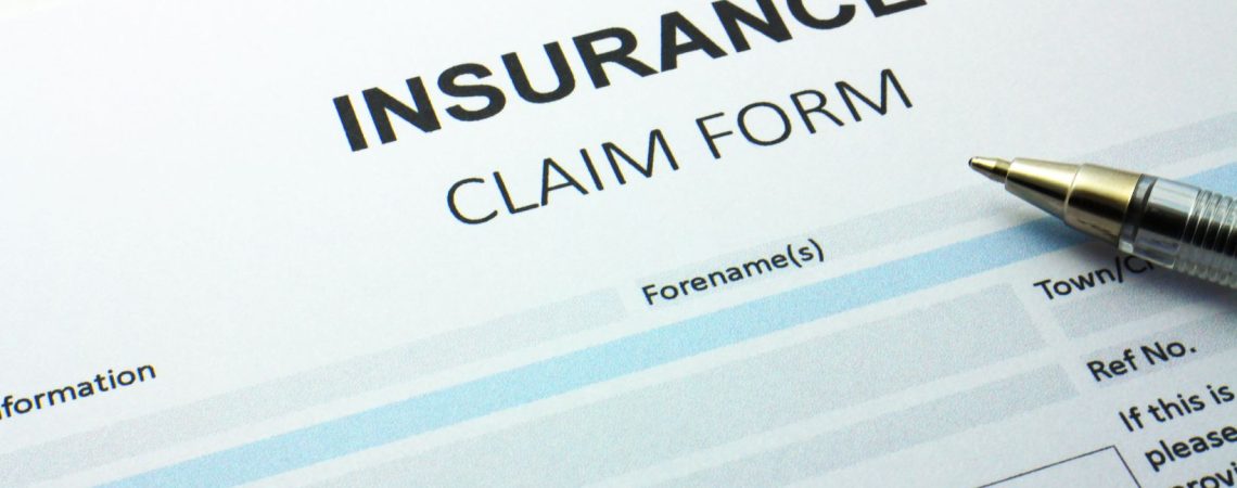 Insurance claim form being filled out with a pen.