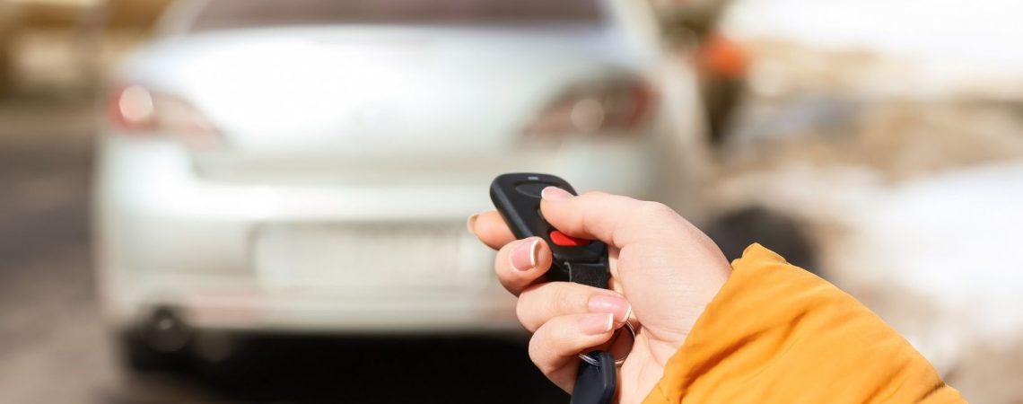 a person holding a car key fob clicking a button for their car