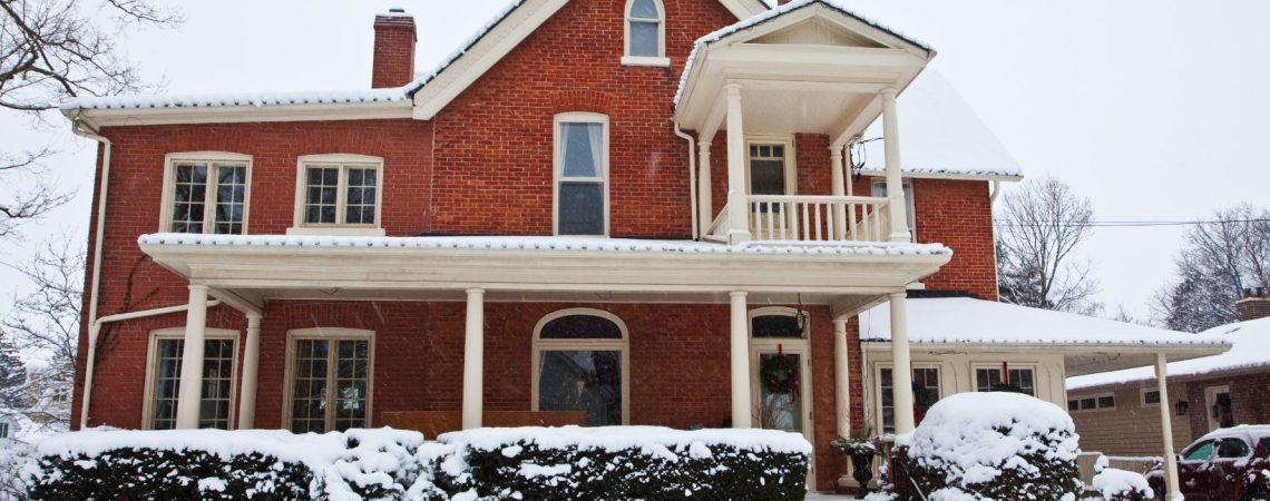 a red bricked home with snow all around it and a car in the driveway