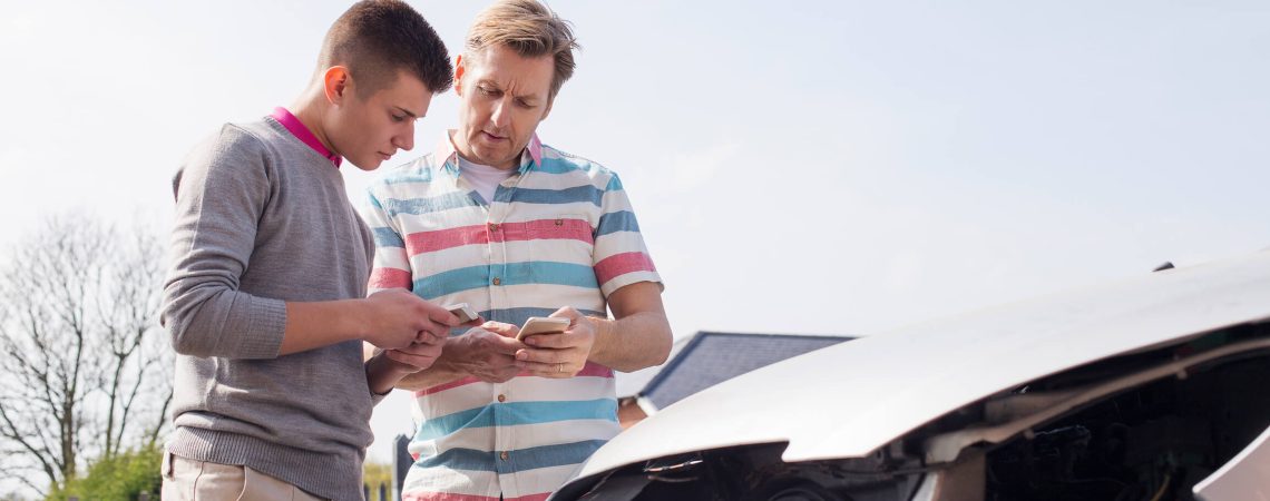 Two people exchanging information in front of a damaged car.