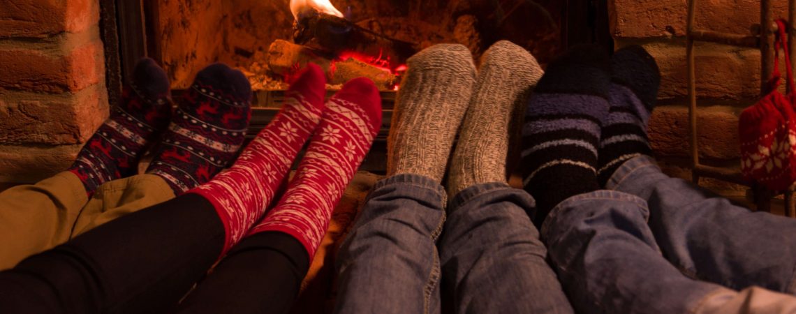 Four pairs of feet warming by a fire