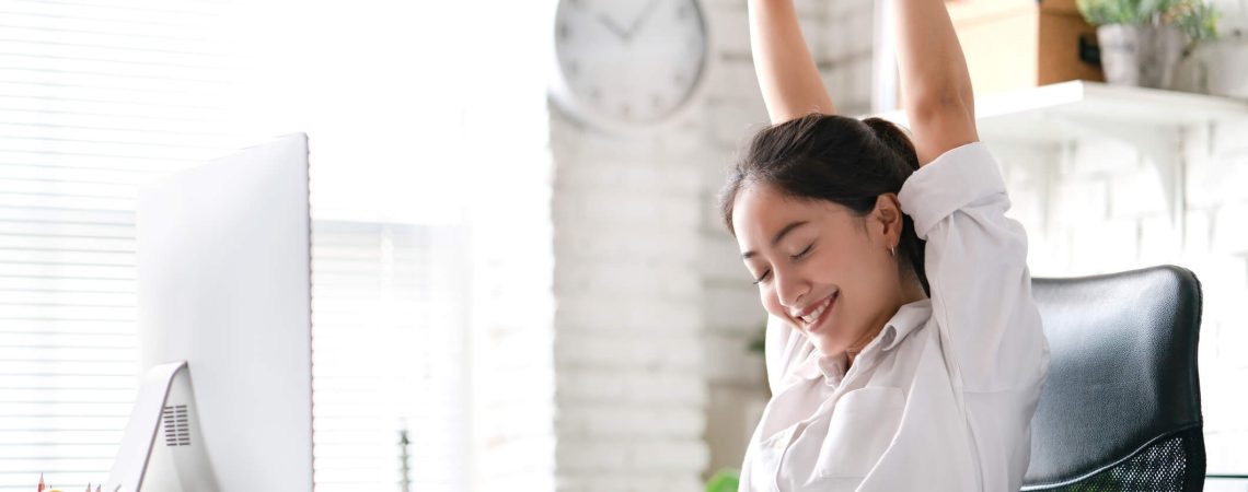 A woman stretching at her work desk