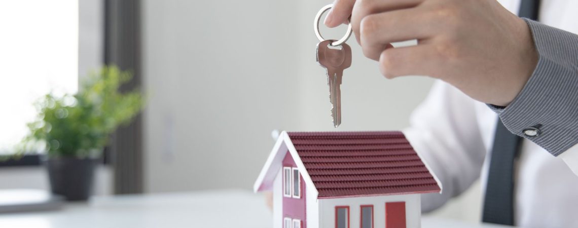 A man holding a key above a house model.