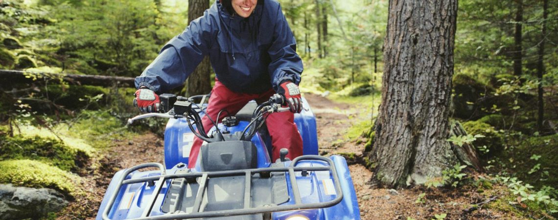 A person riding a atv through a forest.