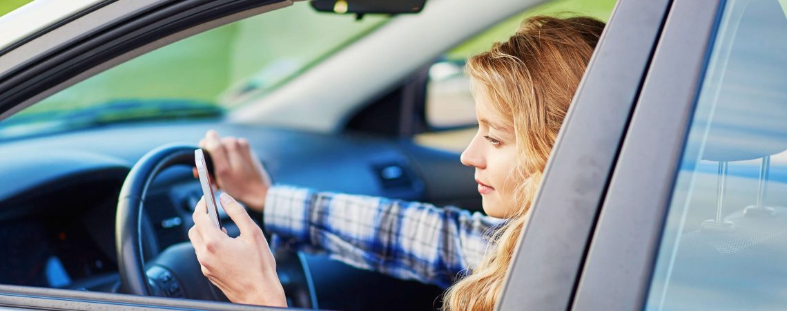 A woman driving while also looking at her phone.