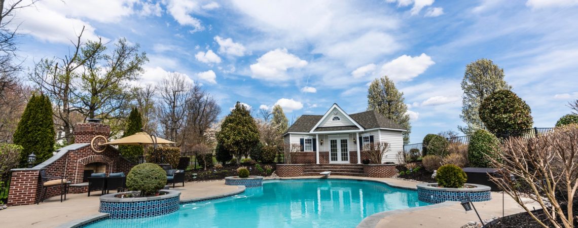 A pool in a backyard with a small pool house.