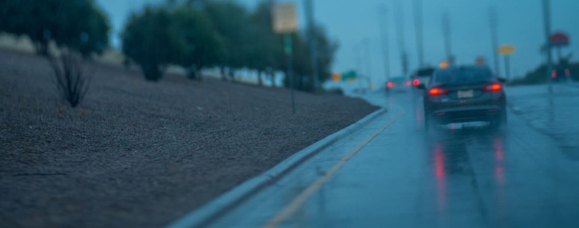 A rainy wet road with cars on it.