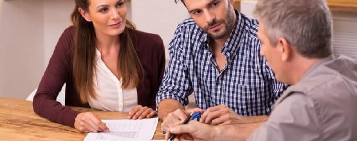 An insurance broker talking to a couple at a table.