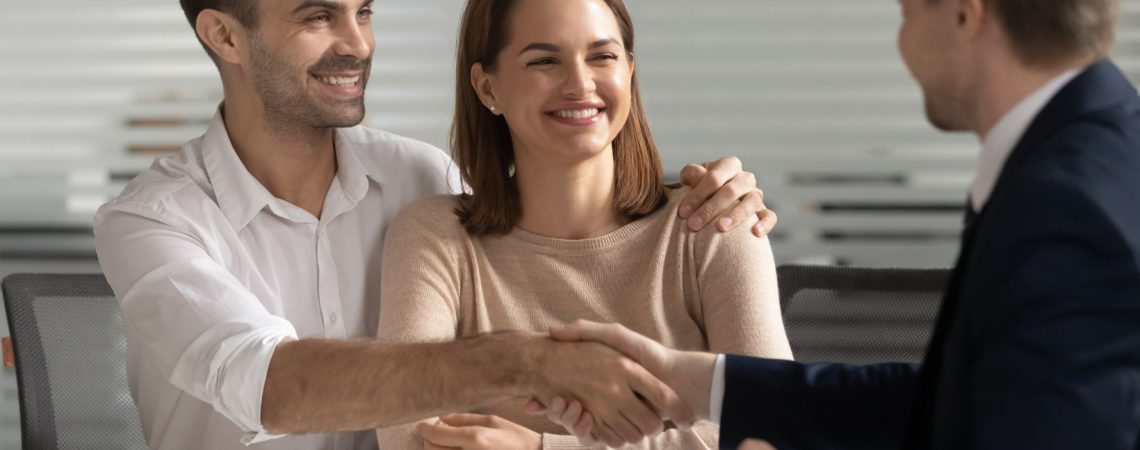 A couple with the man shaking another persons hand.