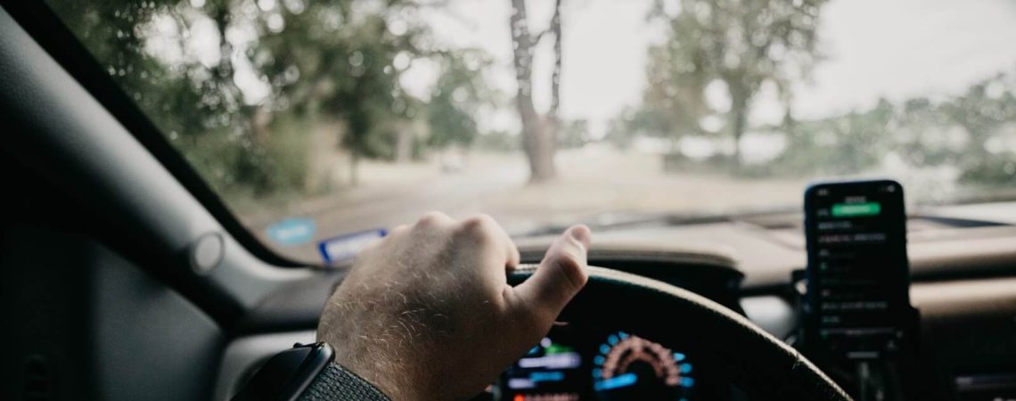 A hand on a car steering wheel