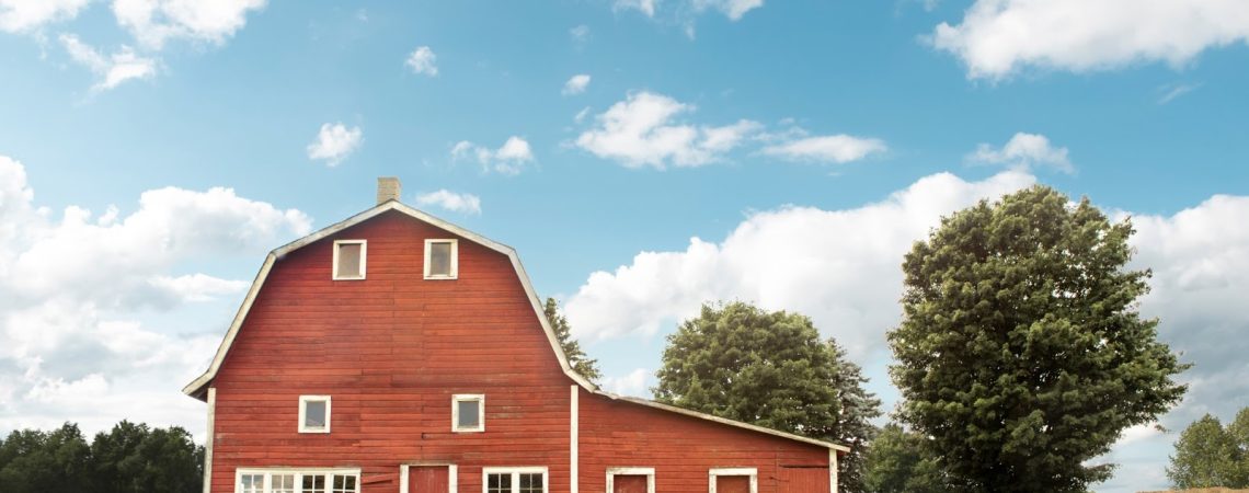 a red barn with blue skies and green grass