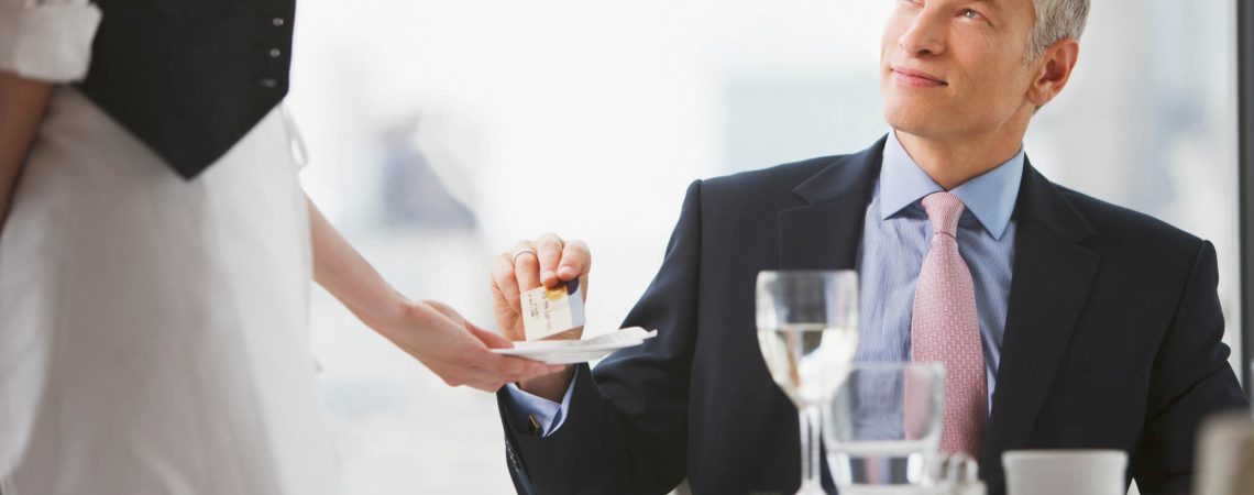 A business man handing a credit card to a waiter.