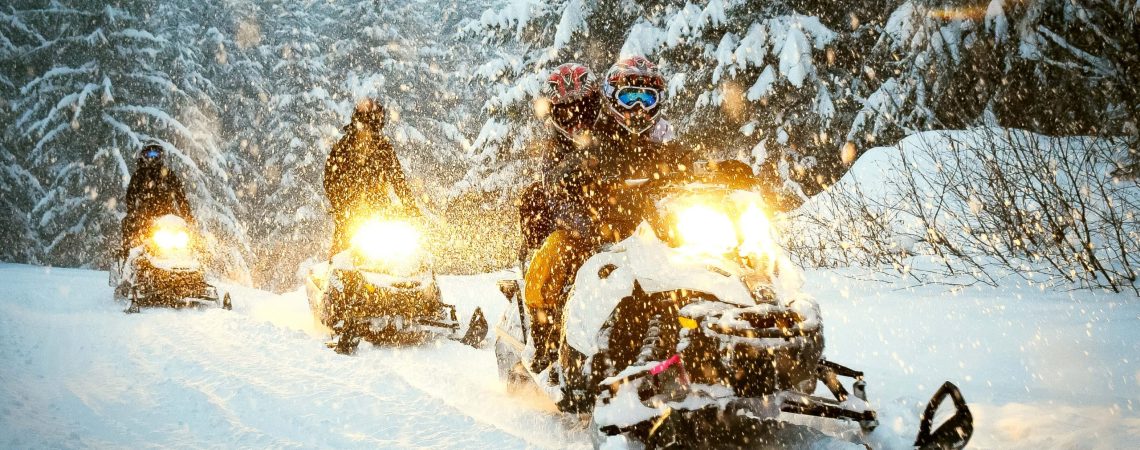 three snowmobiles driving on a trail